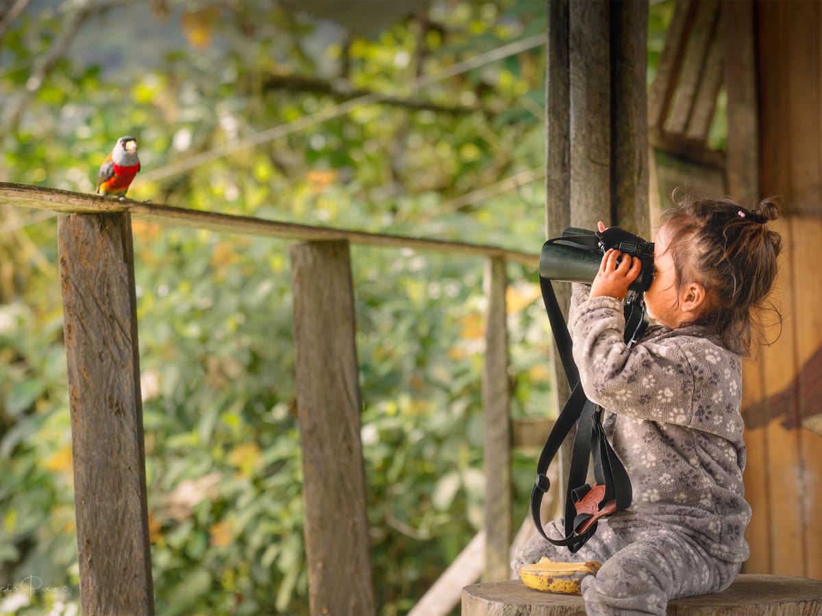 A little girl learns how to use binoculars at Paz de las Aves