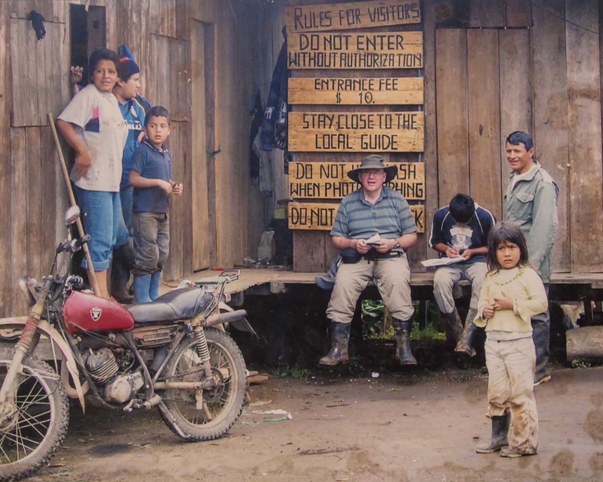 A birdwatcher sits outside of the Paz family cabin with several family members gathered around